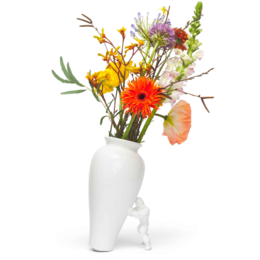 A tall, white ceramic vase with a modern, abstract design. The vase contains a vibrant bouquet of colorful flowers including orange gerbera daisies, yellow wildflowers, and green foliage.