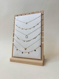 Wooden jewelry display stand with multiple delicate chain necklaces, gold and silver tones, pendant chains.