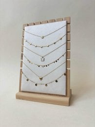 Wooden jewelry display stand with multiple delicate chain necklaces, gold and silver tones, pendant chains.