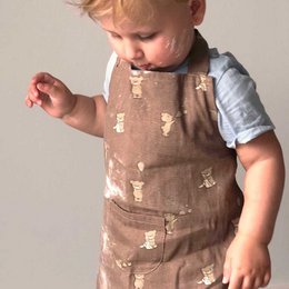 Tan apron with white teddy bear print, made of cotton material, suitable for casual wear.
