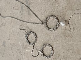 Silver necklace with circular pearl pendant and matching earrings. Elegant and sophisticated jewelry set.