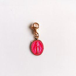 Oval-shaped pink pendant with a religious symbol, made of metal with a gold-tone clasp.