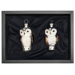 A pair of white ceramic owl ornaments, approximately 6cm in size, displayed in a black framed box.
