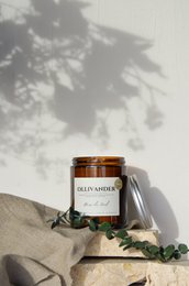 Scented candle with a warm, woody aroma of oud wood. Tall, round shape with a natural, rustic appearance.