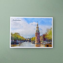 A postcard depicting the Munttoren, a historic tower in Amsterdam, Netherlands. The image shows a colorful, scenic view of the tower and surrounding canal with boats.