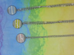 A set of three demi gender pride necklaces with circular pendants in pastel colors on a silver chain.