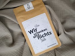  A small brown paper bag with a white label that says "Happy Birthday" in cursive text. The bag appears to contain some kind of tea or other product.