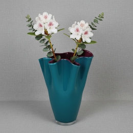 Turquoise and purple glass vase with a wavy, two-tone design. Suitable for displaying on a table or shelf.
