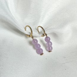 Elegant gold-tone hoop earrings with delicate lavender-colored beads. The earrings feature a simple, minimalist design that complements a variety of outfits.