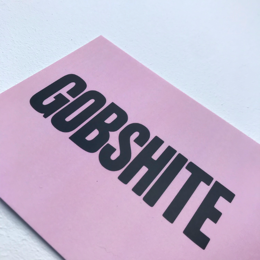 A pink postcard with the text "GOBSHITE" printed in bold black letters.