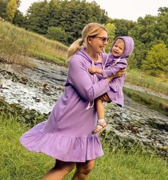 A purple, ruffled dress with a matching purple outfit for a woman and child. The dress has a flowy, feminine silhouette and the woman and child appear to be in a natural, outdoor setting.