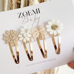 A set of 4 decorative barrettes featuring white and gold floral designs, suitable for children's hair.