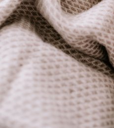 Large, soft, taupe-colored wool blanket or throw with a textured, woven pattern.