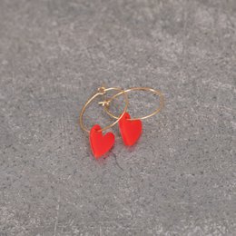 Red heart-shaped charms on gold hoop earrings. Stylish and fashionable jewelry.