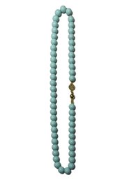 Colorful beaded necklace with round turquoise-colored beads and a gold-colored accent bead.