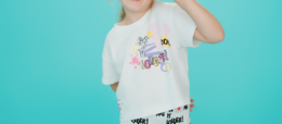 A white short-sleeved kids' shirt with a nature-inspired graphic print featuring flowers, leaves, and a butterfly. The shirt is part of the Ava Aventure collection.