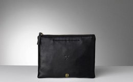 Medium-sized black and white leather clutch bags with zipper closure and minimal branding.