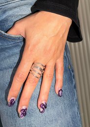 A silver statement ring with a wave-like design, featuring multiple overlapping bands for a bold, modern look. The ring is available in sizes 16, 17, and 18.