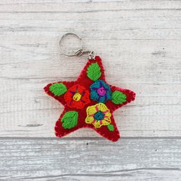 Red star-shaped keychain pendant made of colorful wool with floral design.