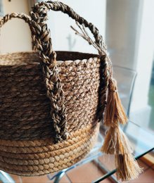 Woven seagrass storage basket with reinforced bottom, 34x30cm in size, featuring tasseled handles and a natural, earthy color palette.