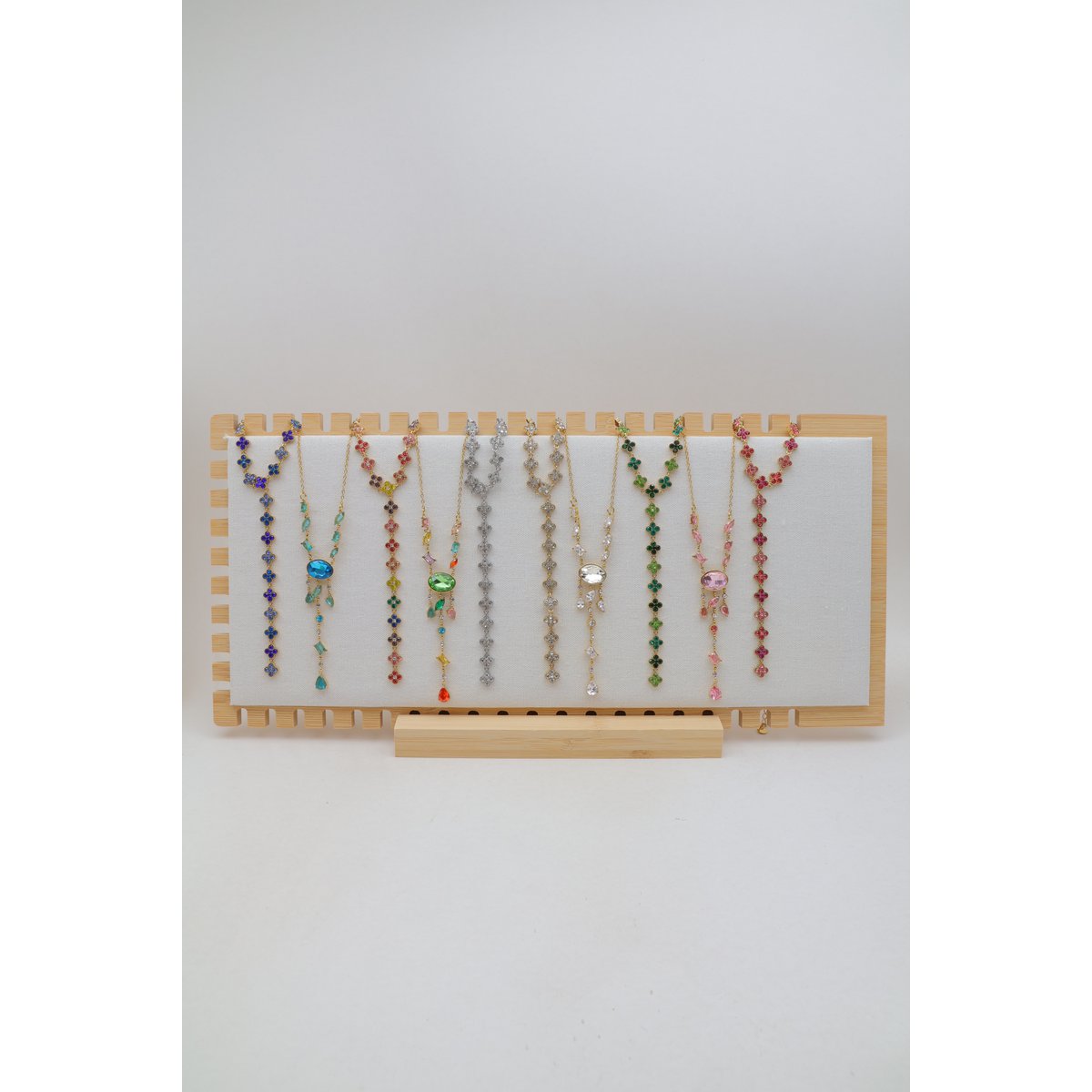 Sélection de 10 colliers en Y en acier inoxydable, disposés sur un présentoir en bois avec socle assorti.