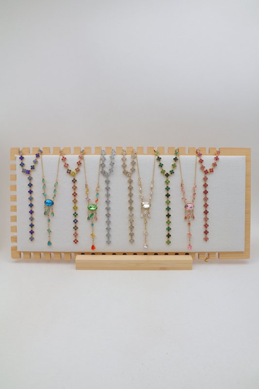 Sélection de 10 colliers en Y en acier inoxydable, disposés sur un présentoir en bois avec socle assorti.
