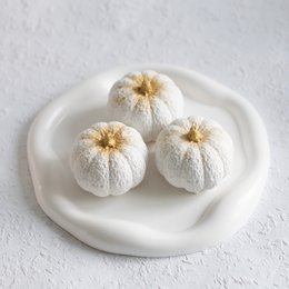 White pumpkin figurines with gold stems, decorative statues for autumn and Halloween.