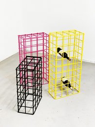 A tall, rectangular wire storage unit in bright yellow and pink colors. The unit has an open grid design and appears to be made of metal or wire mesh. It could be used to store or display various items.