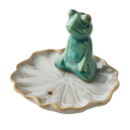 Green ceramic cat figurine on white shell-shaped dish, incense holder, decorative accent piece.