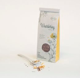 Herbal tea with floral design, featuring a round tea pot and tea cups on a rustic wooden surface.