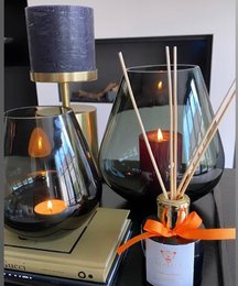 Elegant black glass reed diffuser with gold accents, featuring a tall cylindrical shape and reed sticks for fragrance diffusion.
