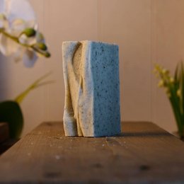 Organic green clay soap bar with natural blue and beige colors, rectangular shape, and textured surface.