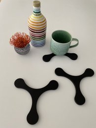 Black abstract coasters with a curled, organic shape. Made of durable material suitable for use as cutting boards or trivets.