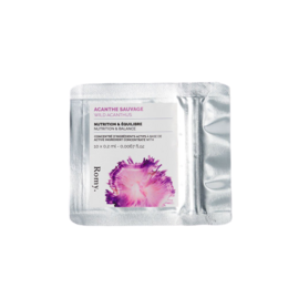 A pink and white capsule-shaped product in a clear plastic package. The product appears to be a cream or skincare item.