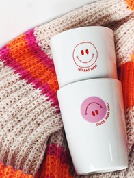 Ceramic mug with smiley face design, available in various color combinations including black, rosa, and rot. The mug features a handle and a cheerful, positive message.