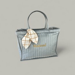 Silver grey quilted mother's bag with a bow accent and leather handles.
