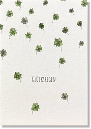 Greeting card with scattered green four-leaf clovers on a white background, conveying a sense of luck and good fortune.