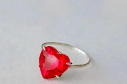  A sparkling red heart-shaped gemstone set in a silver ring.