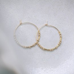 Hoops Fernweh - Gold-tone hoop earrings with beaded accents
The image shows a pair of gold-tone hoop earrings with small beaded accents along the hoop. The earrings have a simple, minimalist design that would complement a variety of outfits. The beaded details add a touch of texture and visual interest to the classic hoop shape.