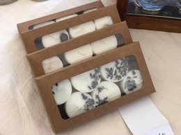 Tealight candles in various scents and styles, including unscented options. The candles are presented in a wooden display case with compartments for different varieties.
The product images show a set of tealight candles in a wooden display case. The candles come in a variety of scents and styles, including unscented options. The display case has multiple compartments to organize the different tealight varieties, such as "Tealights sweater weather", "Tealights laundry day", "Tealights fall in love", "Tealights dark forest", "Tealights not today", "Tealights no scent", "Tealights I sea", and "Tealights summer vibes". The candles appear to be made of a light-colored wax material.