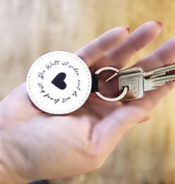 Handmade vegan leather keychain with the saying "The world is beautiful because you are in it" in a round shape.