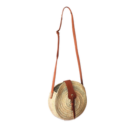 Round natural woven palm bag with cognac leather shoulder strap, Moroccan handicraft style.