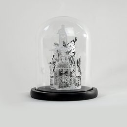 A miniature glass dome containing a detailed black and white illustration of a whimsical aviary scene, featuring various birds and architectural elements. The product is available in two sizes, "mini edition" and "classique edition".