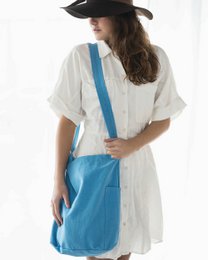  A white cotton dress with a blue canvas shoulder bag. The bag has a simple, minimalist design with a single strap.