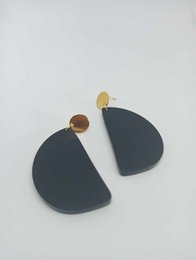Black matte acrylic drop earrings with gold accents.