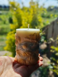 Tall, round, yellow candle with a floral design.