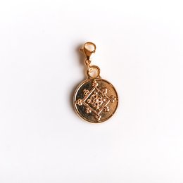 Circular gold-toned pendant with intricate floral design.