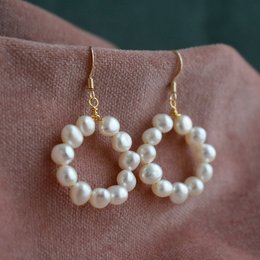Elegant pearl hoop earrings with a classic and timeless design. The earrings feature a circular shape adorned with a cluster of small, lustrous pearls, creating a beautiful and feminine look.
