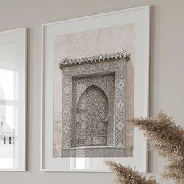 The image shows an ornate architectural detail, likely from a building in a Middle Eastern or North African style. The focal point is a decorative arched doorway or window frame, featuring intricate geometric patterns and ornamental elements. The overall style suggests a traditional Islamic or Moorish architectural influence.