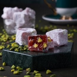 Soft, chewy Turkish delight with a pomegranate flavor, dusted with powdered sugar and garnished with pistachios.